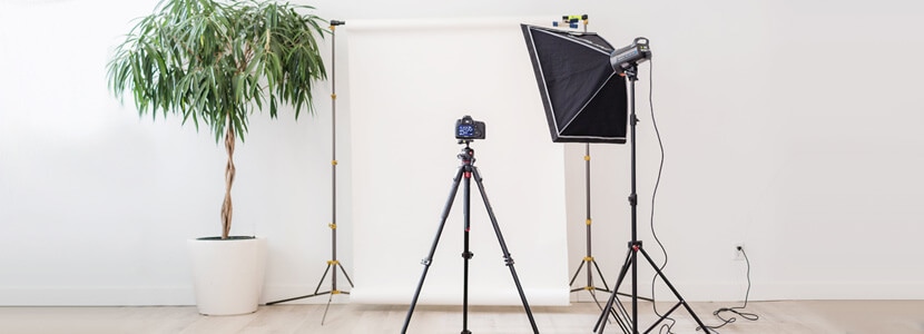 Simple in-house photography studio setup with a camera, lighting equipment, and white backdrop for ecommerce photography