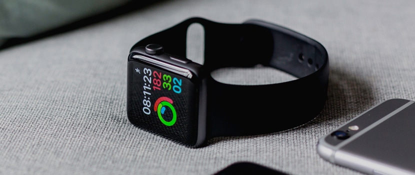Close-up of a smartwatch showing activity rings and notifications on a gray surface