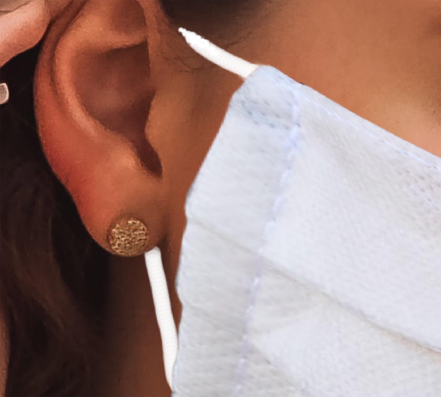 Close-up view of white mask strap positioned behind ear next to textured earring.