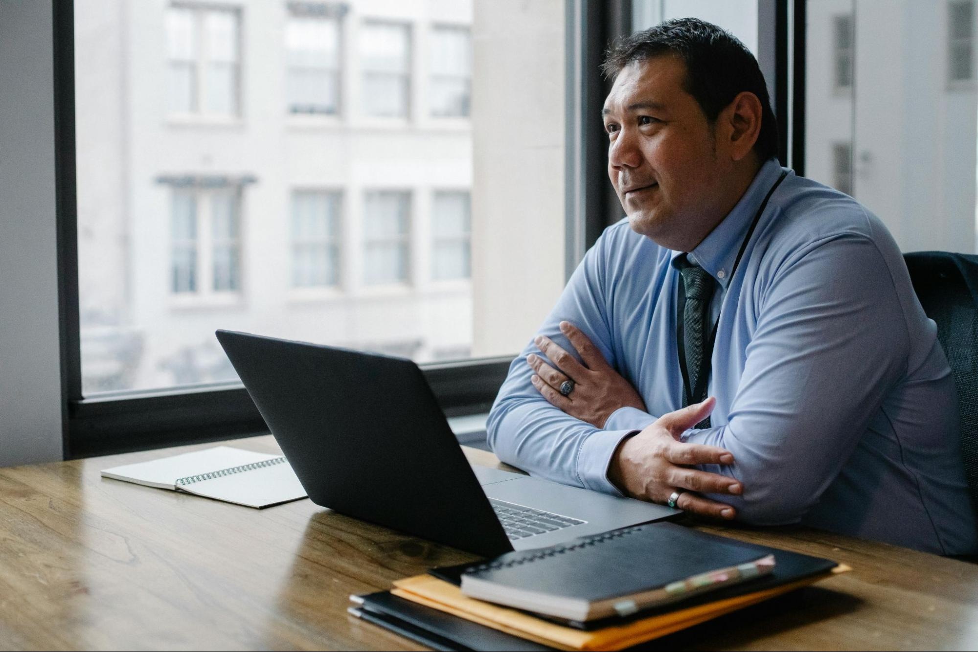 man sitting at a desk looking away from the camera with an open laptop in front of him