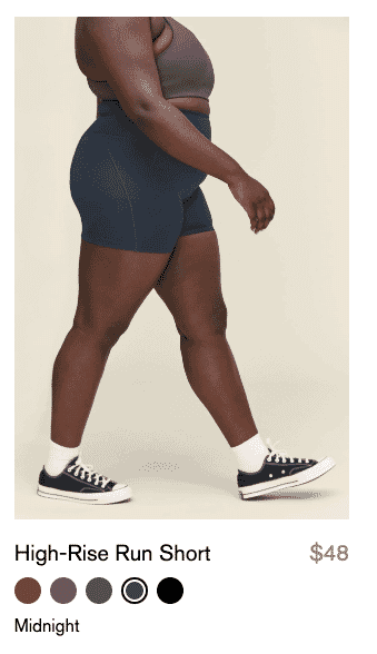 Side view of model wearing high-rise run shorts in midnight color with a dark sports bra and sneakers.