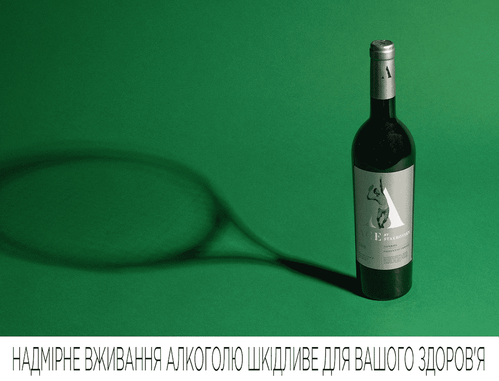 Stakhovsky wine bottle casting a shadow on green background with health warning in Ukrainian