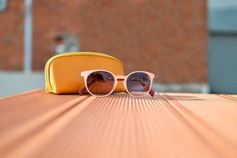 Final image of sunglasses and pouch on table after background object removal using GIMP Clone Tool.