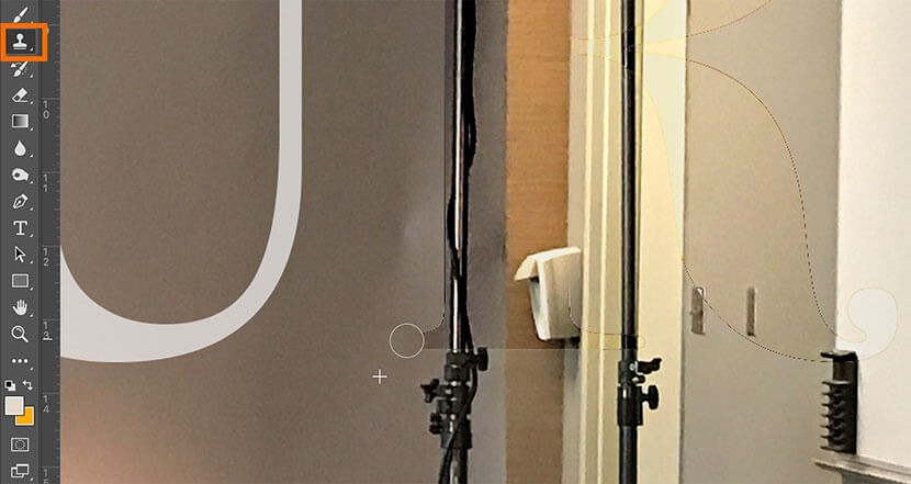 Photoshop Clone Stamp Tool selected for detailed touch-up on a studio backdrop image.