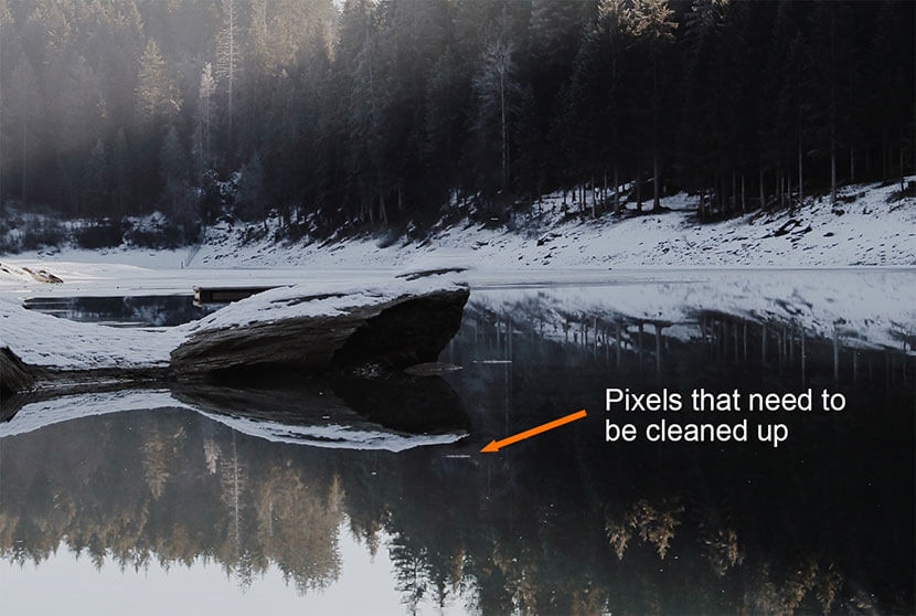 Remaining pixels marked for cleanup after object removal in a lake scene using Photoshop