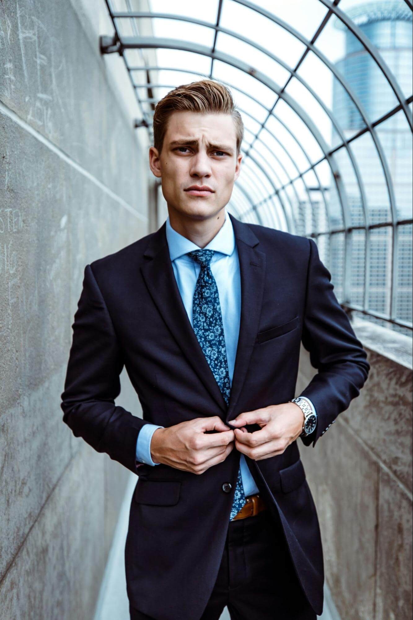 Man in a suit standing in an outdoor setting, exuding confidence and a natural expression