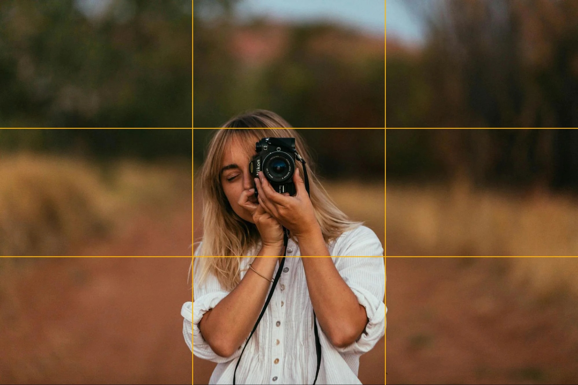 A portrait photographer applying the rule of thirds, capturing a subject with a camera in an outdoor setting.