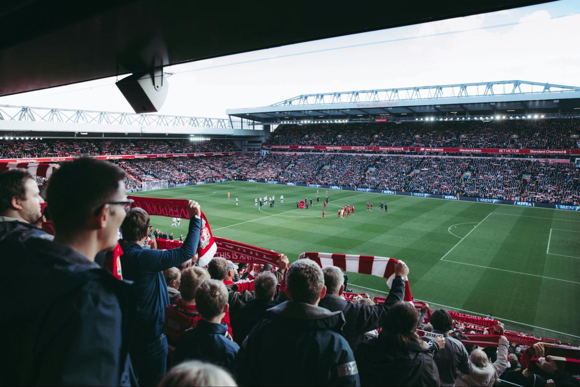 Crowd cheering at a soccer stadium during a live game, capturing fan energy and stadium atmosphere
