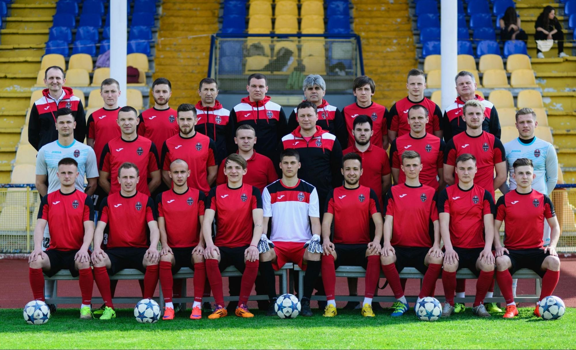 Soccer team group photo taken on-site with players and coaches arranged in rows