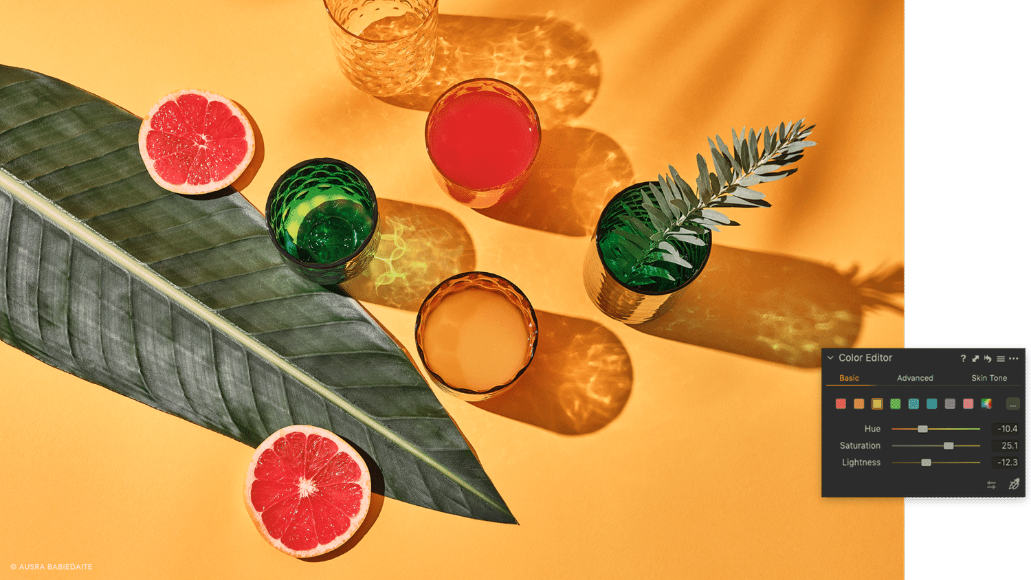 Still life photo of colorful glasses, grapefruit, and leaves on yellow backdrop, edited in Capture One for enhanced hues.