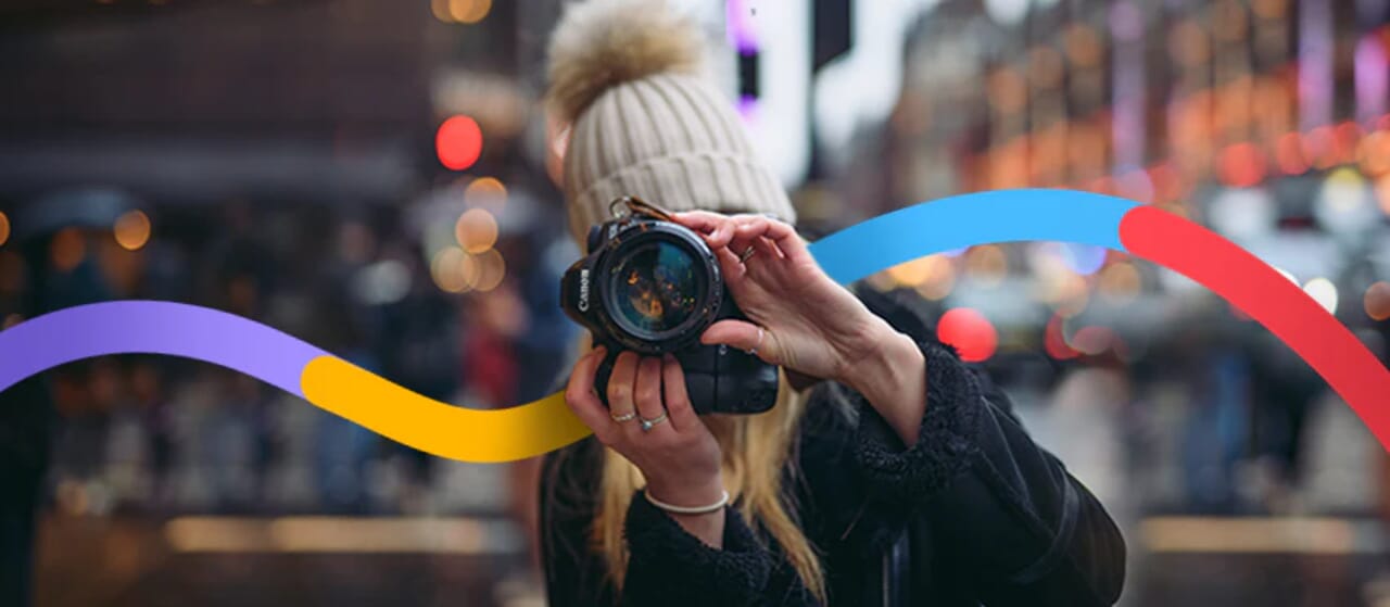 Female photographer in winter hat capturing a street scene with a Canon camera, colorful wave overlay